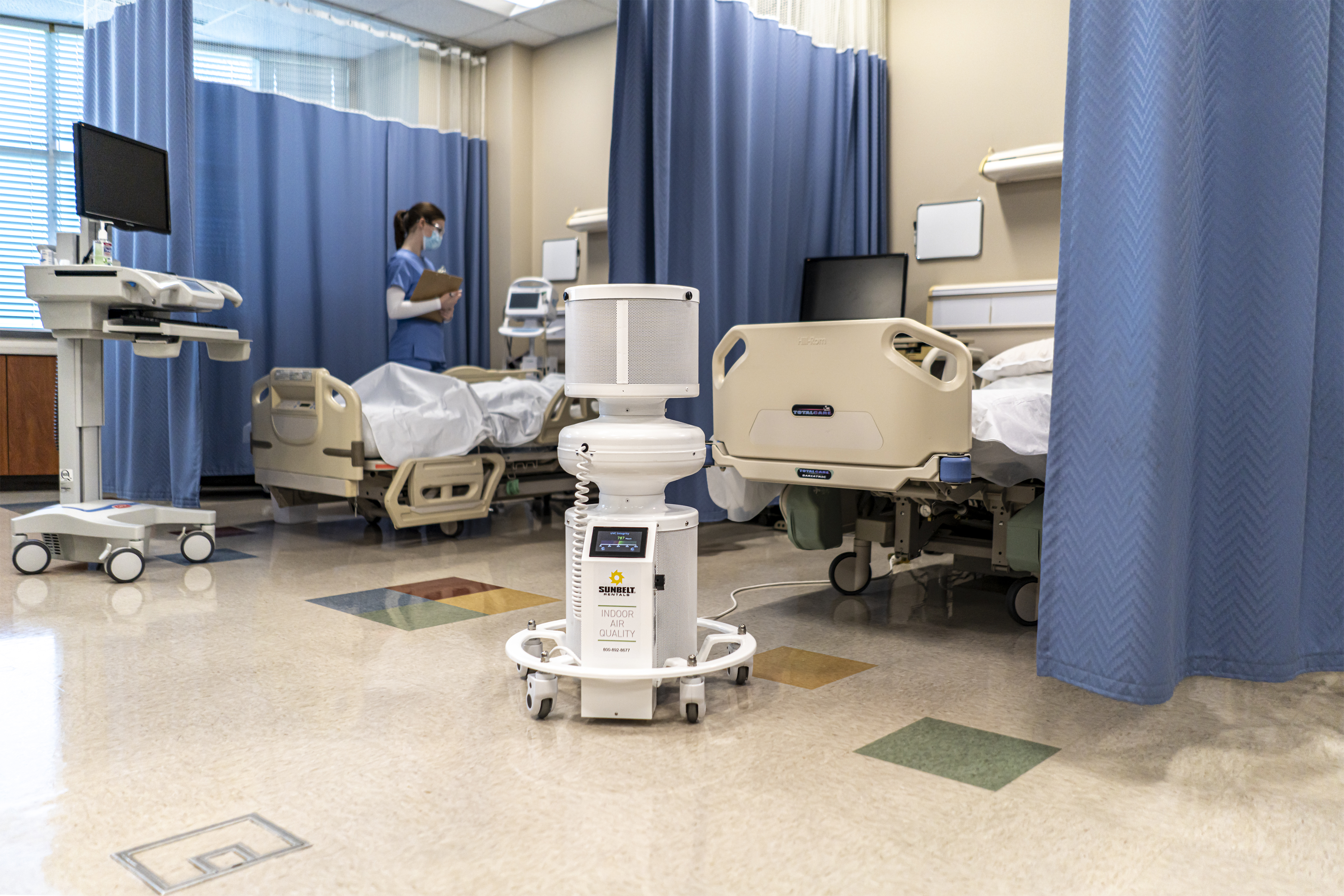 An air scrubber in a hospital room, with a nurse in the background.