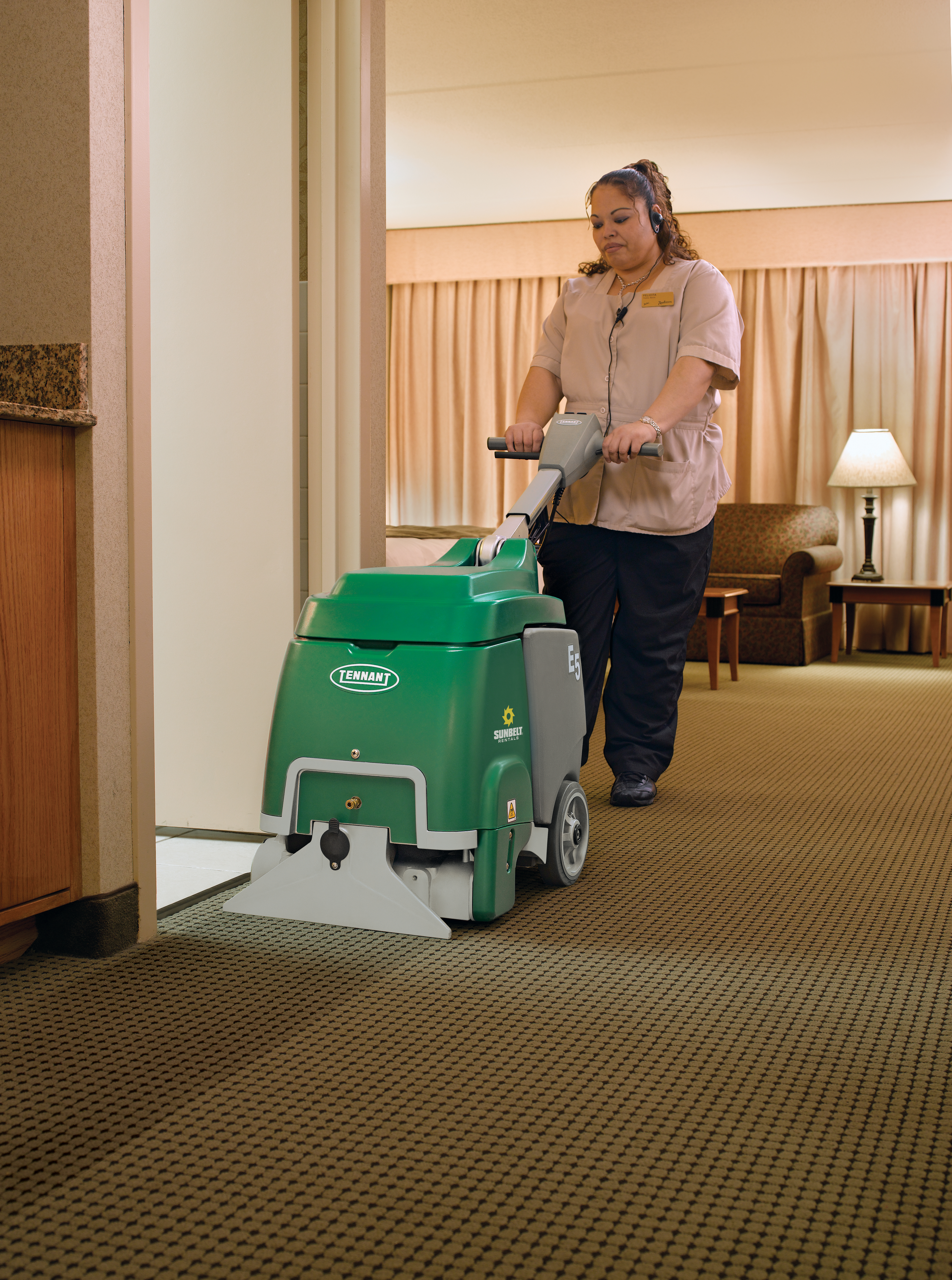 Someone operating a carpet extractor from Sunbelt Rentals inside of a commercial space.