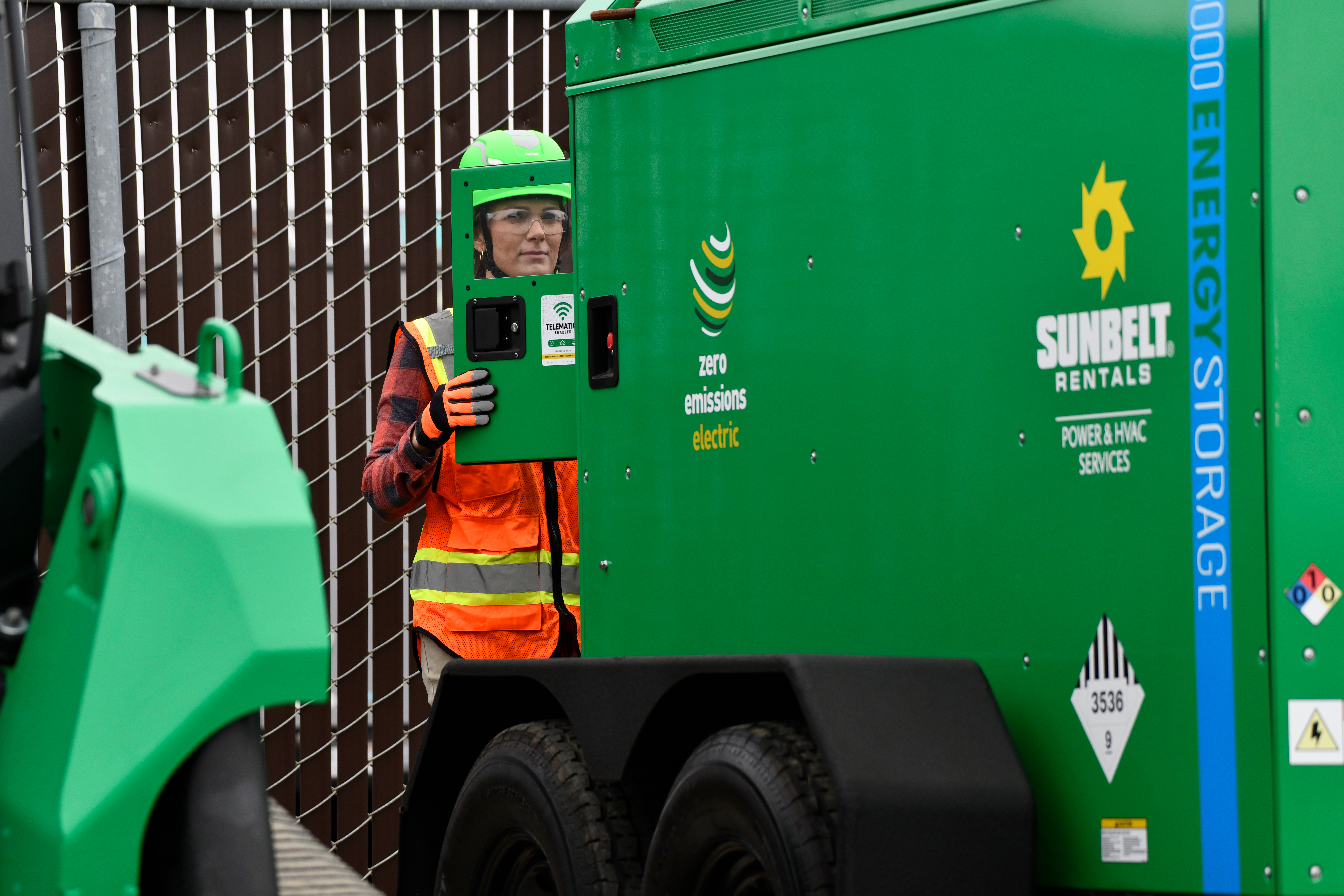 A green energy storage unit from Sunbelt Rentals is shown in an outdoor industrial setting.