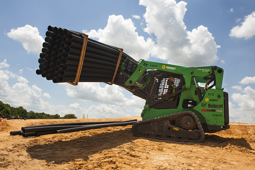 A skid steer loader transporting materials at a job site.
