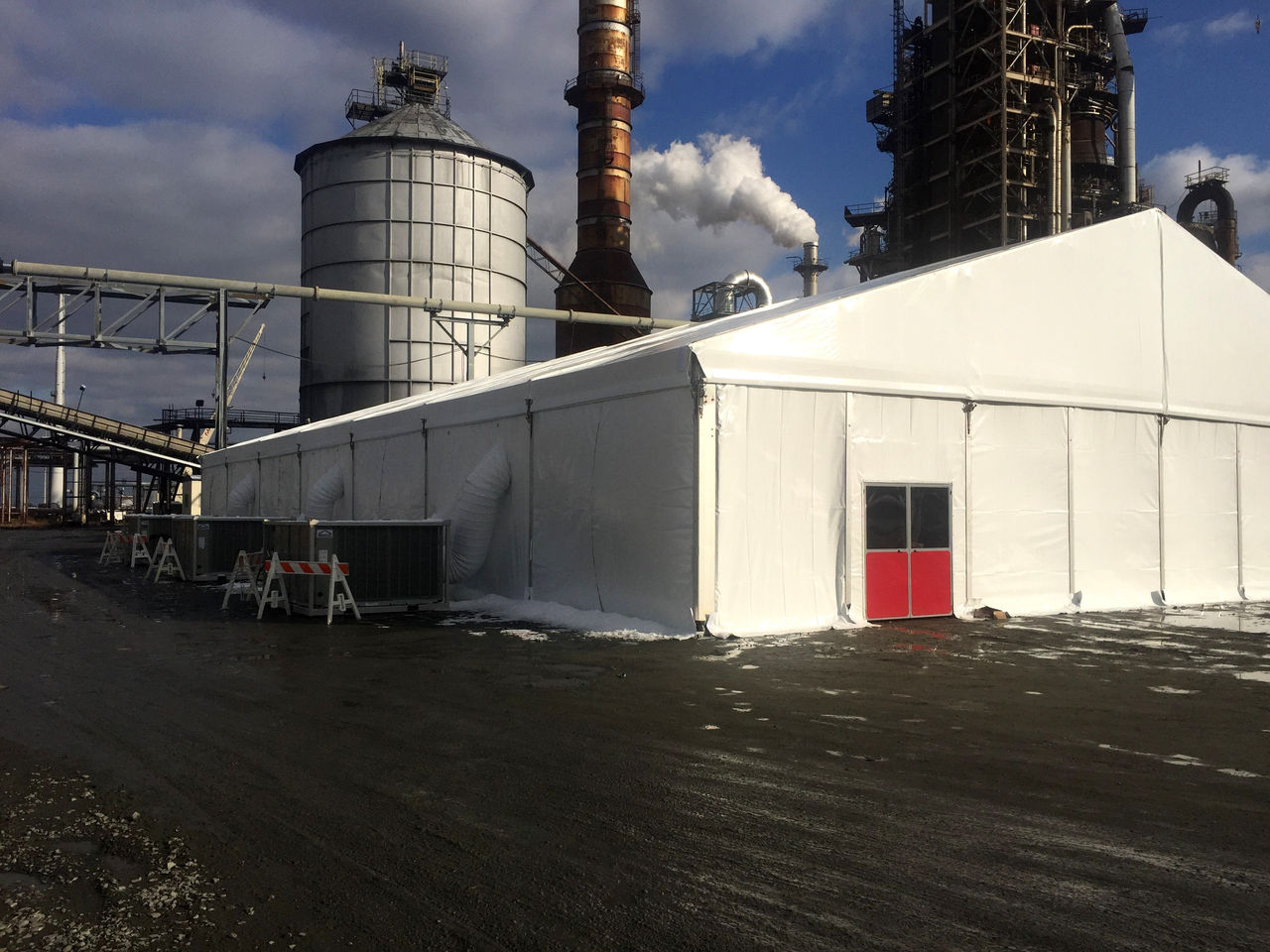 A spacious white temporary structure in an industrial setting.