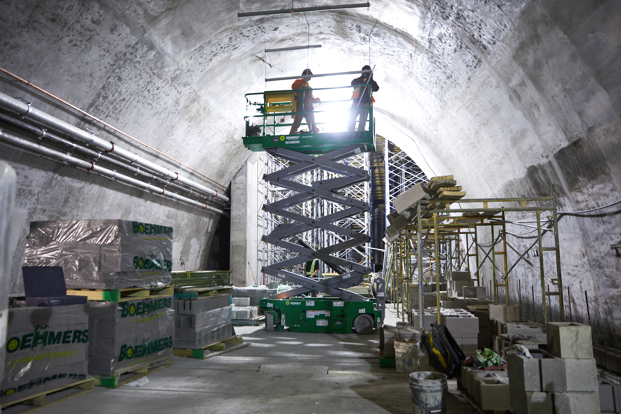 Two people working from a scissor lift in a tunnel.