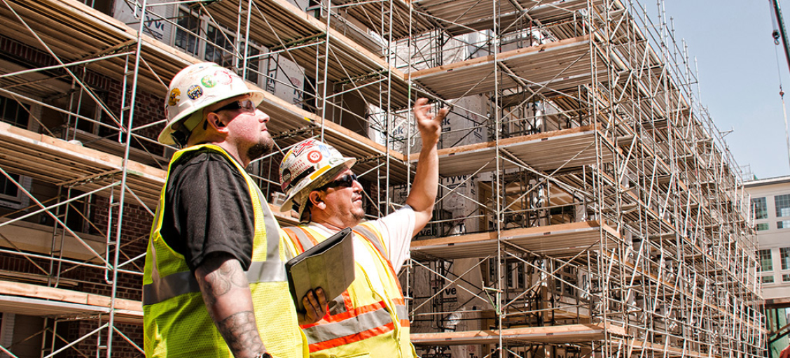 Two construction workers discussing scaffolding project.
