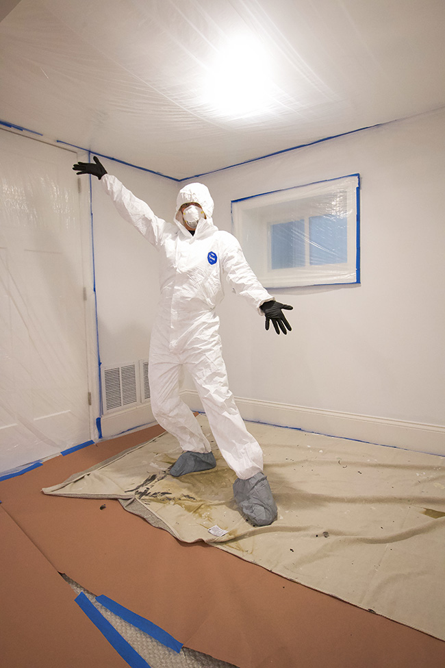 Person wearing safety equipment posing in a room under renovation.